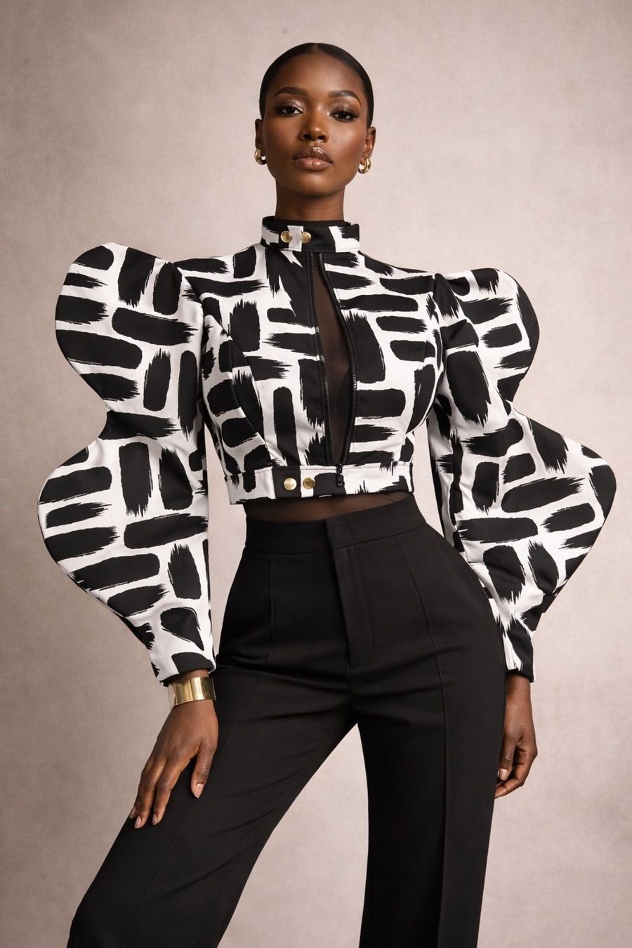 Model in a black and white brush-print puff-sleeve crop top and black wide-leg trousers against a beige studio backdrop